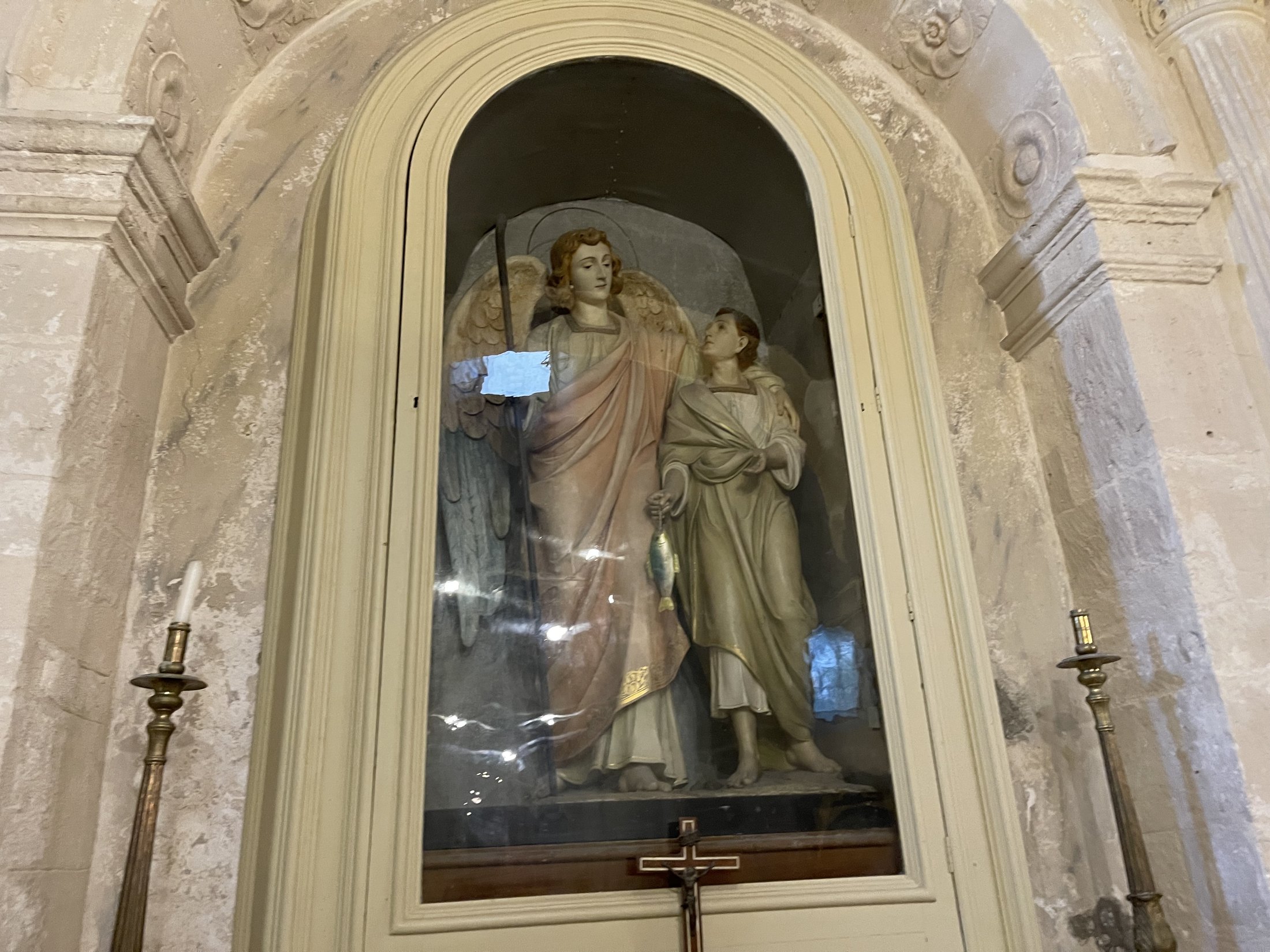 Gruppo scultoreo policromo dell'arcangelo Raffaele che accompagna il giovane Tobiolo, entro una nicchia con vetrina e cornice di stucco