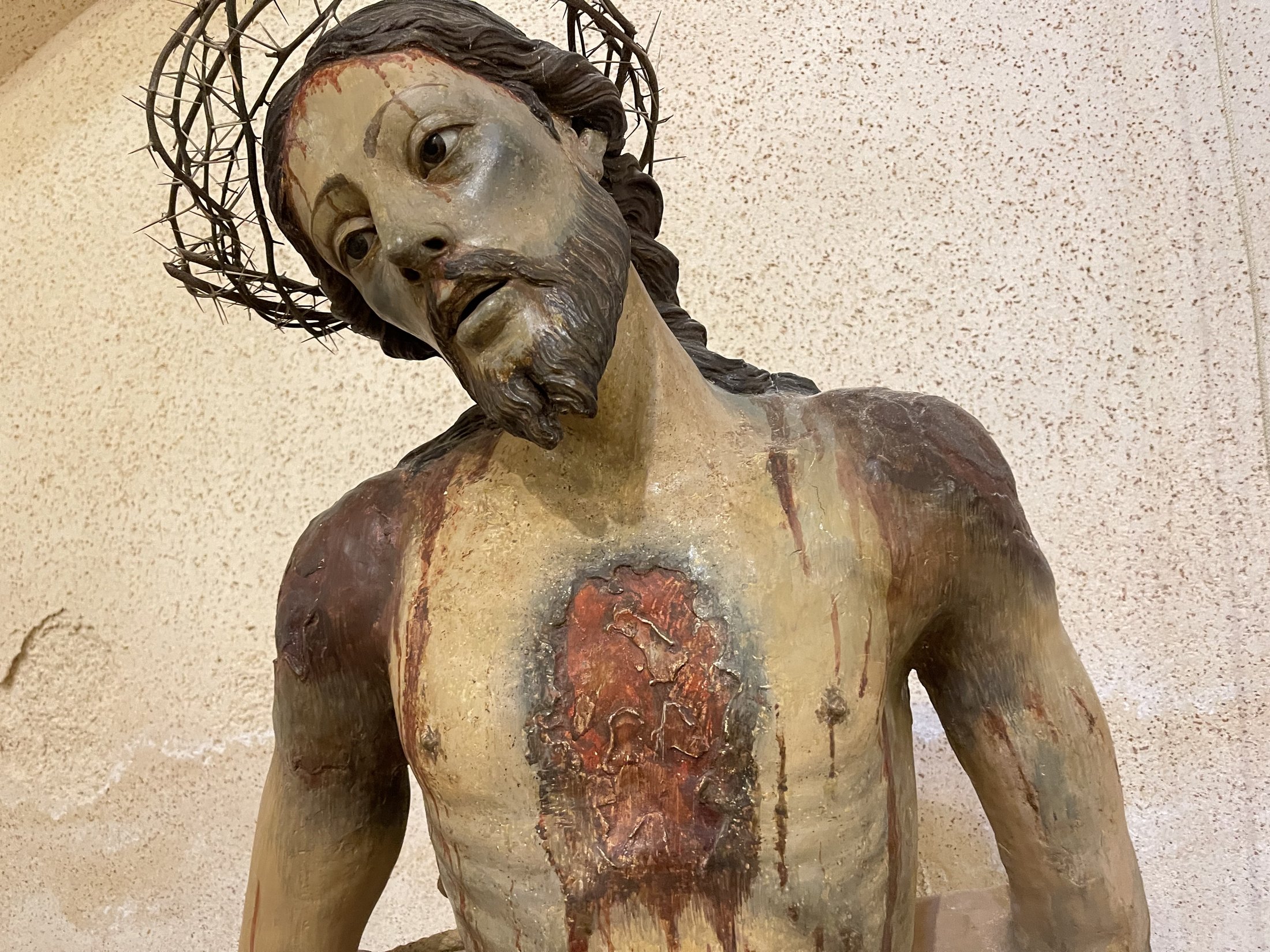 Busto della statua dell'Ecce Homo: volto sofferente con corona di spine, capelli lunghi e piaghe dipinte sul petto