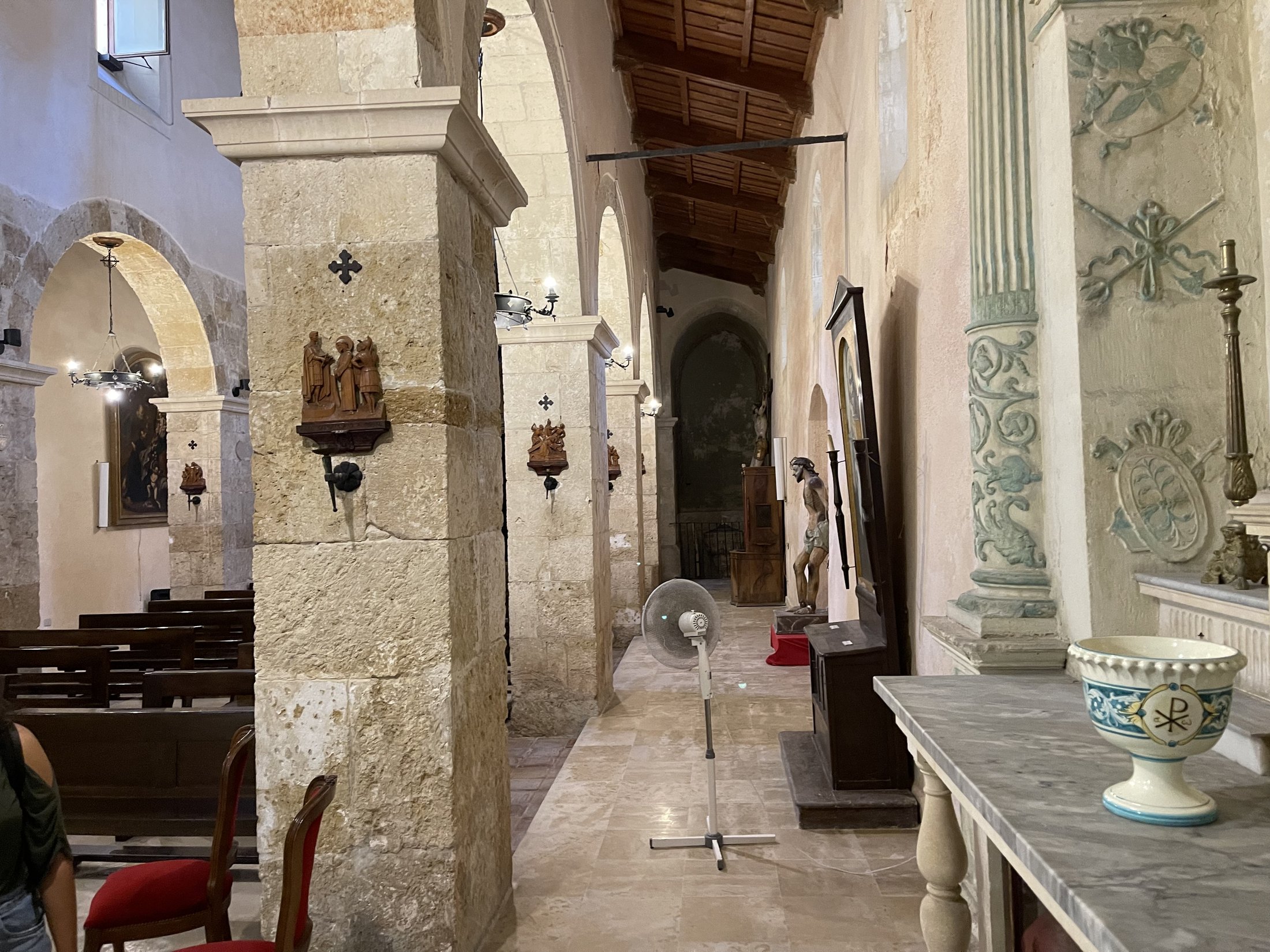 Navatella con pilastri in conci, altare barocco con decorazioni verdi e acquasantiera in primo piano