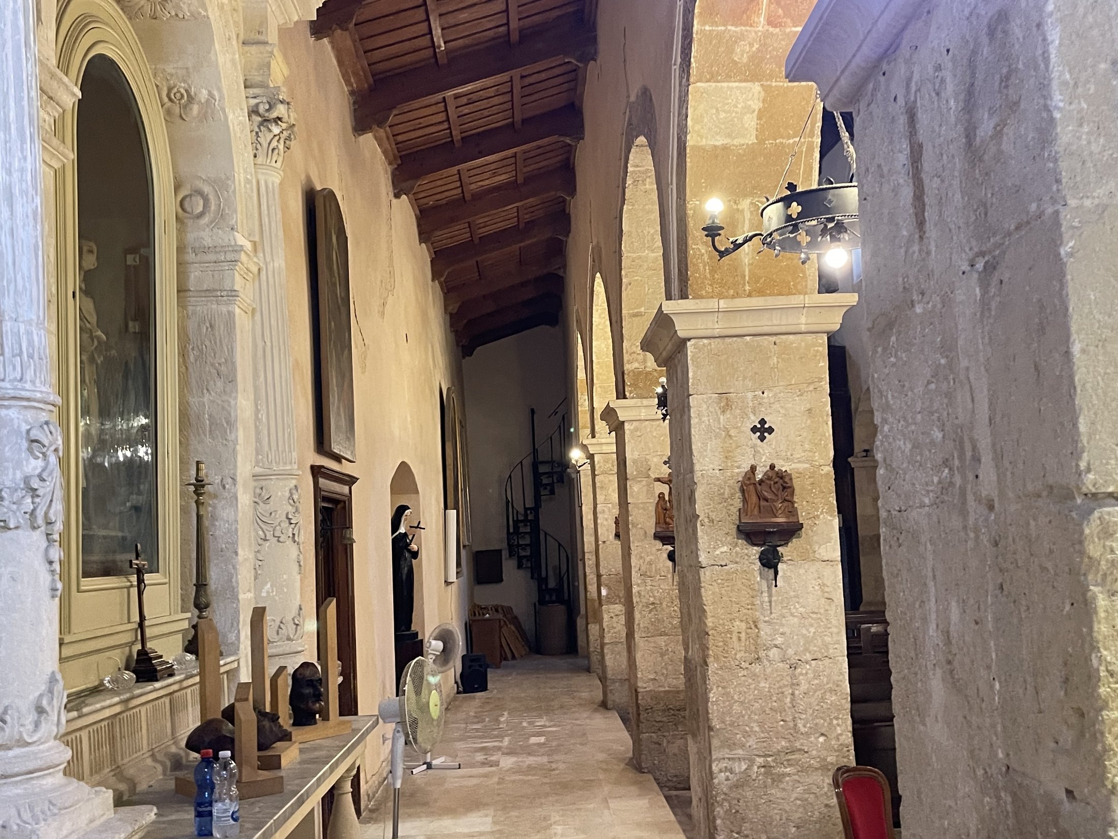 La navatella meridionale con i pilastri in conci, la statua di Santa Rita nella nicchia, le stazioni lignee della Via Crucis e in fondo la scala a chiocciola di ferro
