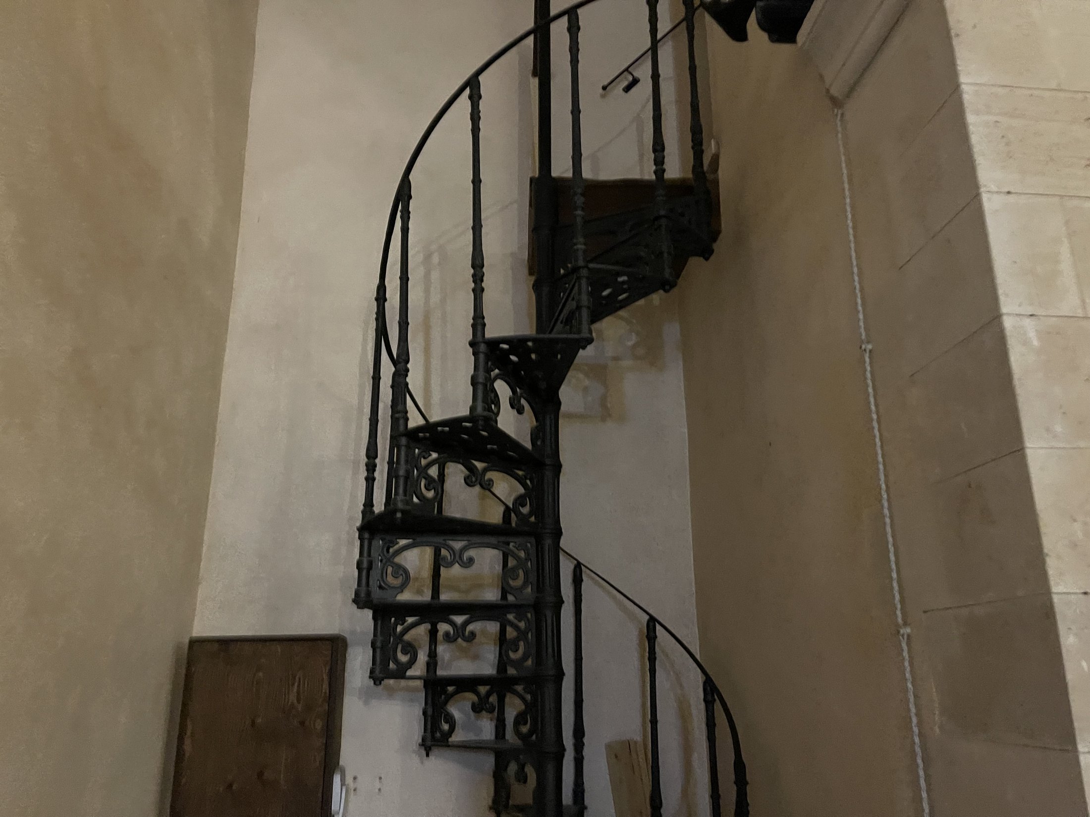 Scala a chiocciola in ferro battuto con gradini traforati e ringhiera a volute, che sale verso la cantoria