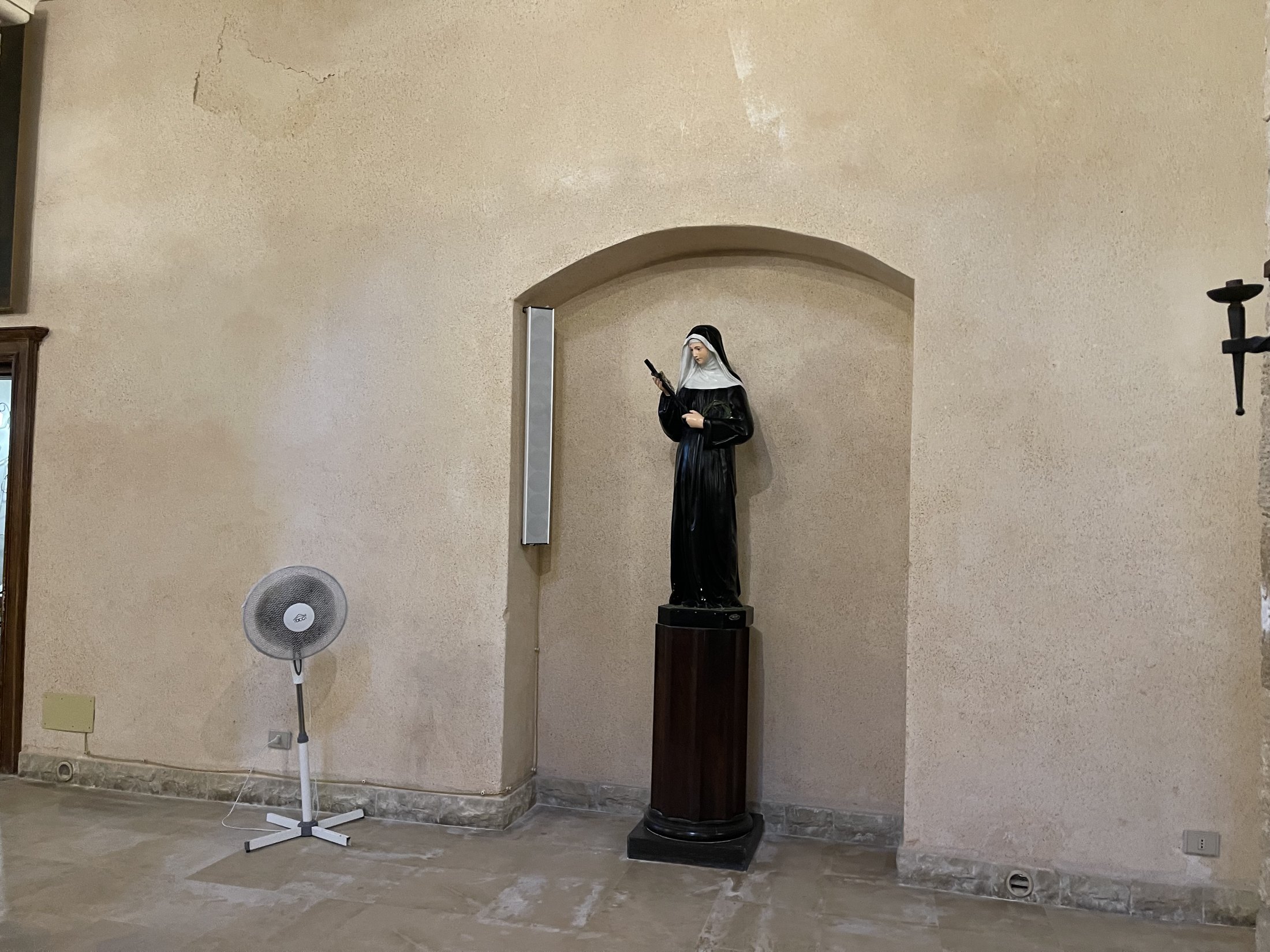 Statua policroma di Santa Rita da Cascia in abito monastico, su piedistallo ligneo, entro una nicchia ad arco