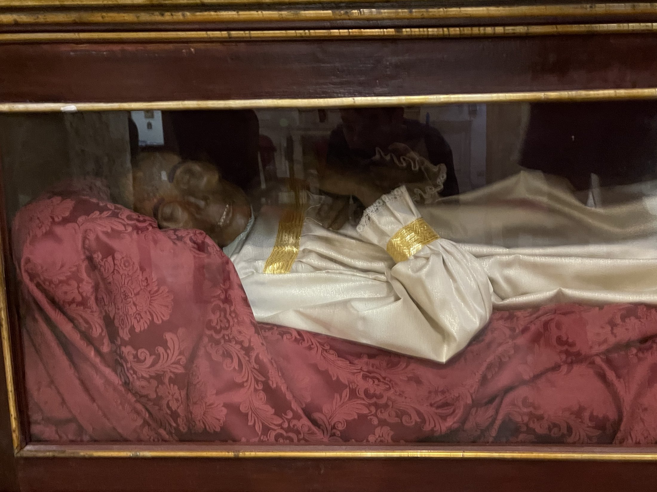 Dettaglio dell'urna con il drappo di velluto rosso e la veste bianca e dorata del martire