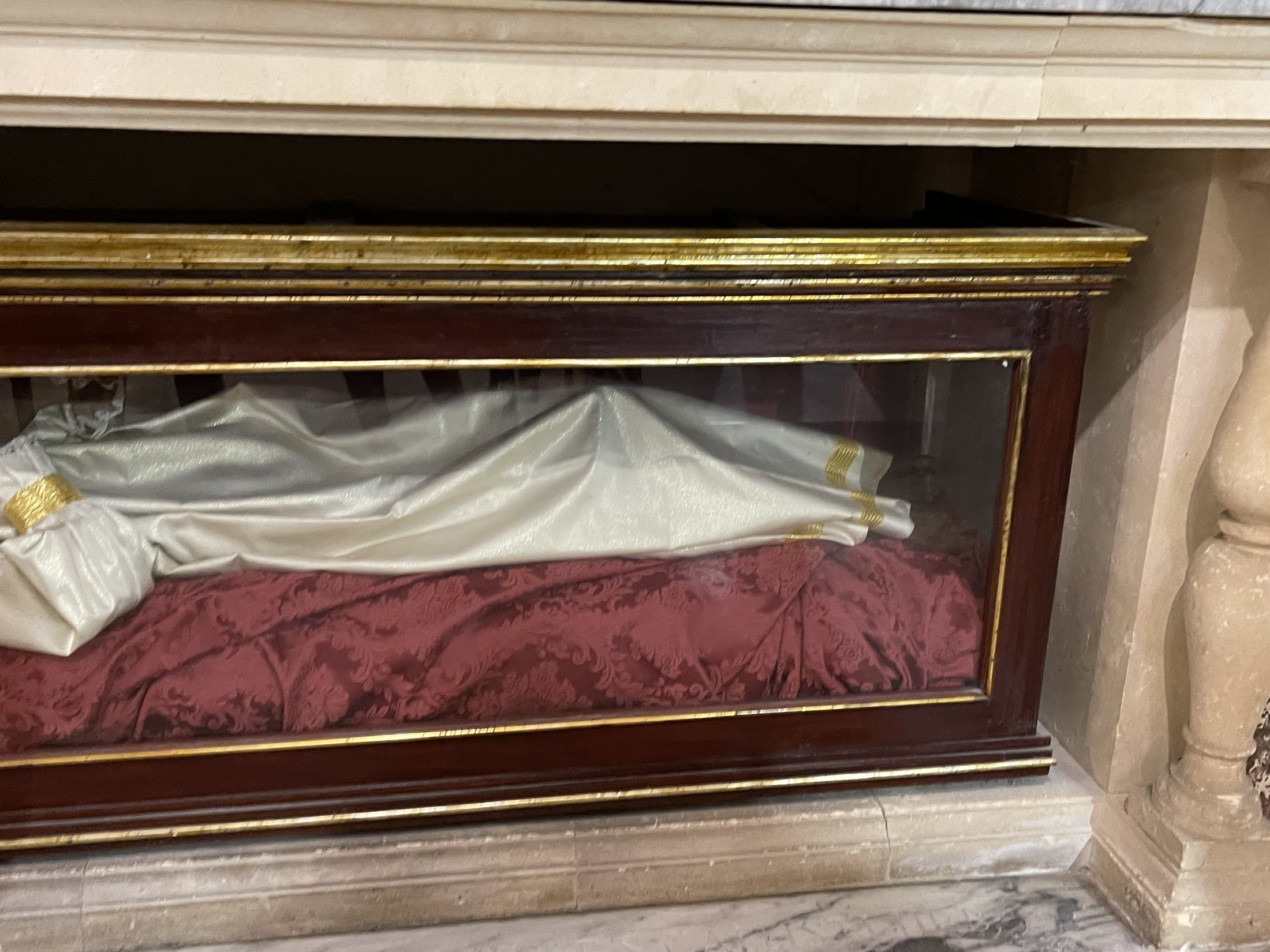 Urna di vetro con cornice dorata contenente il corpo vestito di San Vincenzo martire, adagiato su velluto rosso